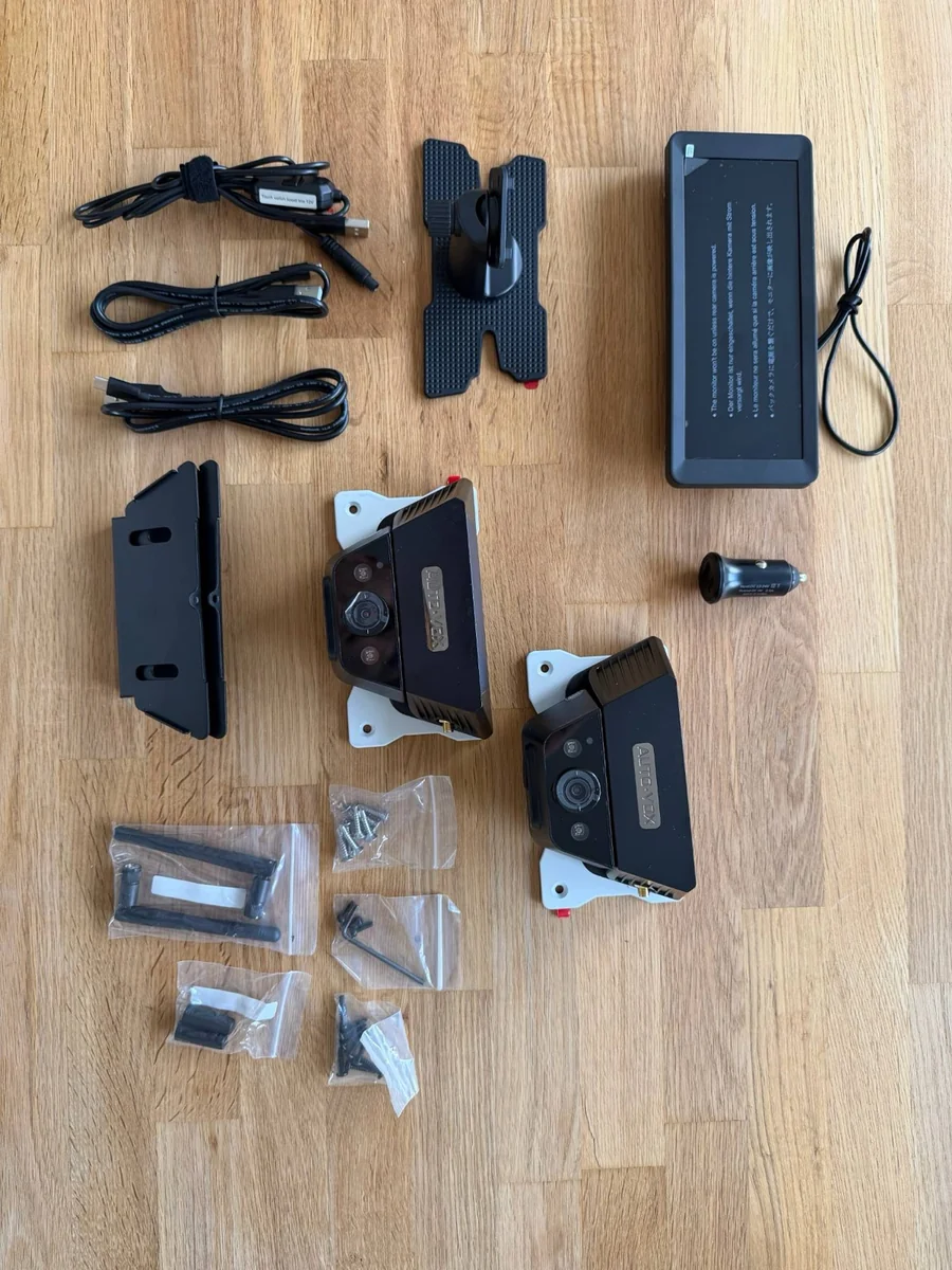 Lieferumfang des Zwei-Kamera-Sets: Monitor, zwei Kameras auf Montageplatten, Halter, Kabel, Antennen und Schrauben
