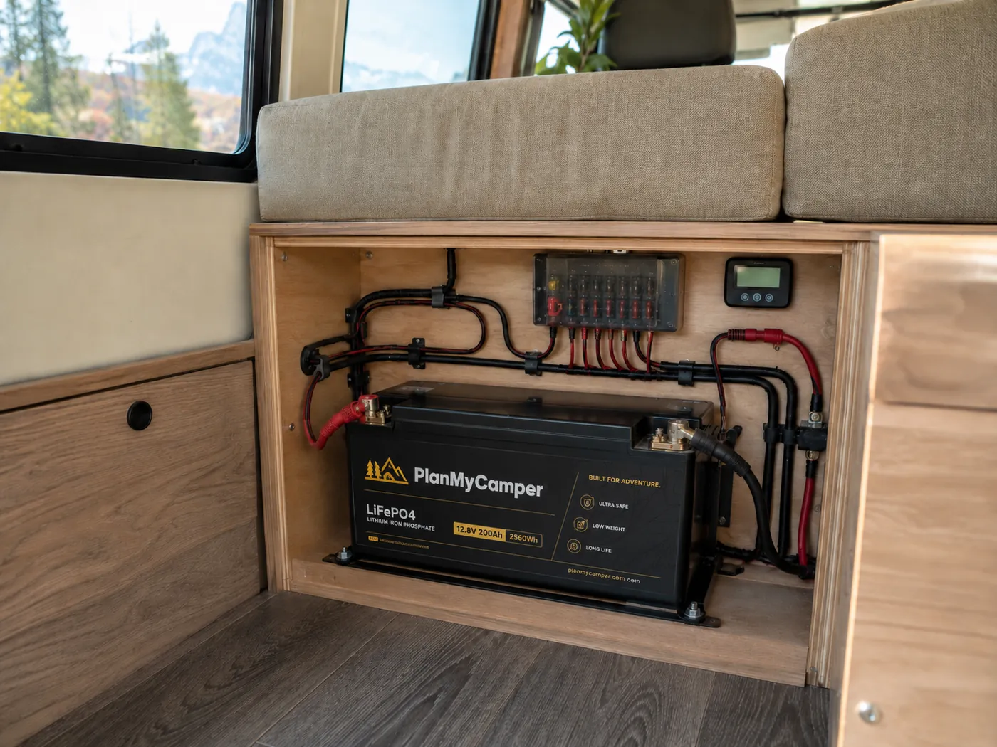 LiFePO4-Versorgungsbatterie sauber unter der Sitzbank eines Camper-Ausbaus verbaut, mit Sicherungskasten und Batteriemonitor